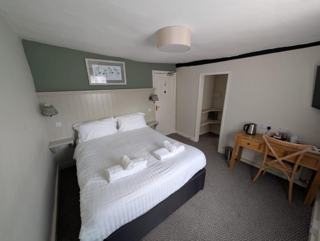 a bedroom with a bed with white sheets and pillows at The Bull Hotel in Downton