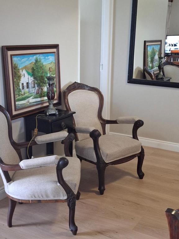 two chairs and a table in a room with a mirror at Notre Petit Paradis in Mossel Bay