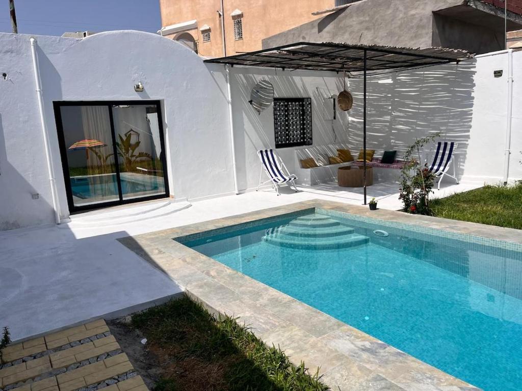 una piscina con un ombrellone accanto a una casa di Hammamet Pool House a Hammamet