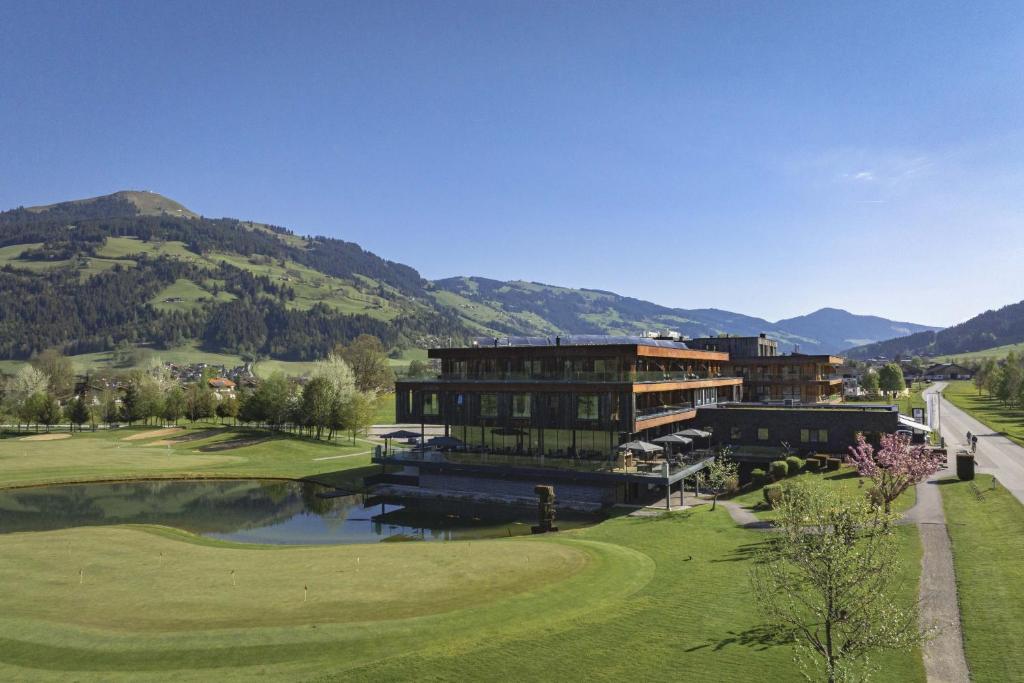 a building on a golf course with mountains in the background at Berg & Golf Resort Westendorf by ALPS RESORTS in Westendorf