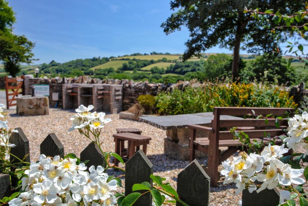 a garden with a picnic table and flowers at Tregolls Farm Cottages in Wadebridge