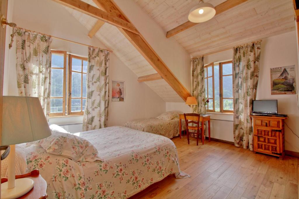 una camera con 2 letti, una scrivania e finestre di Bel Arrayo - gîte d'accueil de montagne - chambres d'hôtes a Cauterets