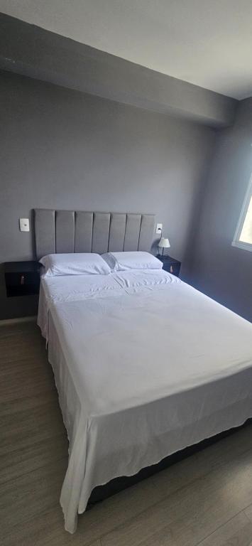 un grand lit blanc dans une chambre avec une fenêtre dans l'établissement Ape wifi, easy access Dutra, Shopping, GRU, à São Paulo
