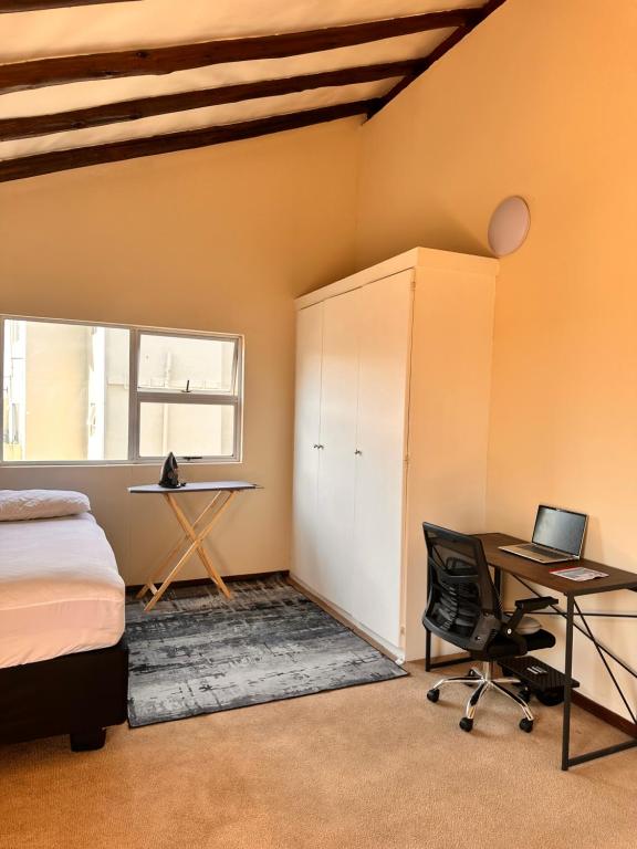 Un dormitorio con una cama, un escritorio y una computadora. en Balcony Bliss, en Johannesburgo