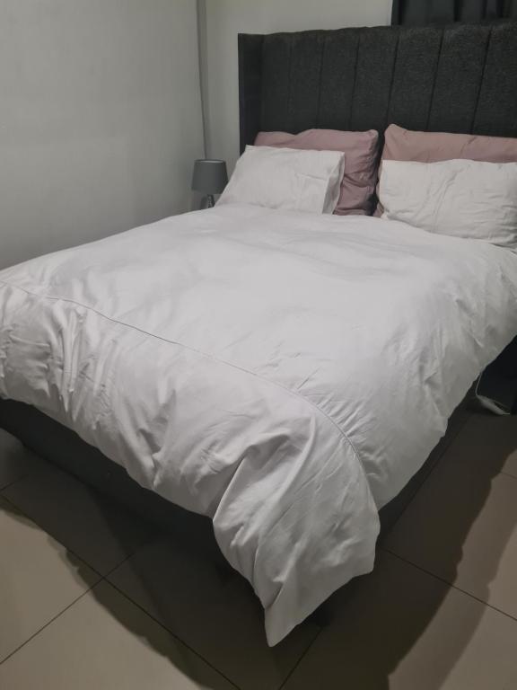 a large bed with white sheets and pillows at Ryder Masai Lofts in Farmall