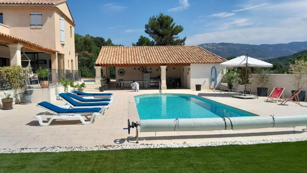 una piscina en un patio con sillas y una casa en Villa L'ecrin Du Ventoux, en Crillon-le-Brave