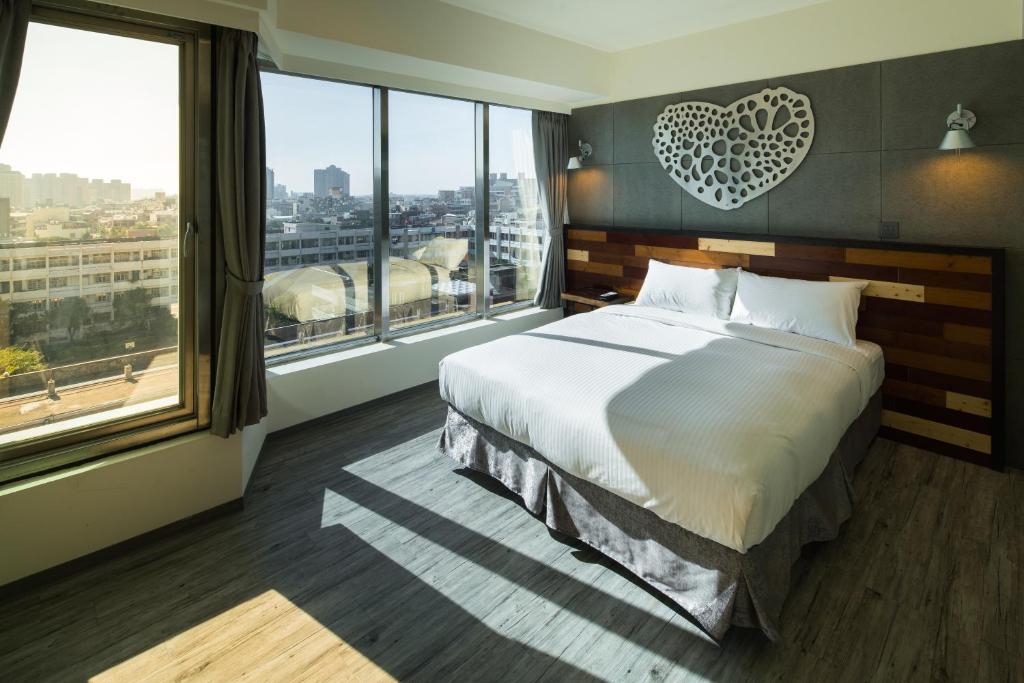 um quarto com uma cama grande e uma janela grande em Xinshe Hotel - Hsinchu em Hsinchu
