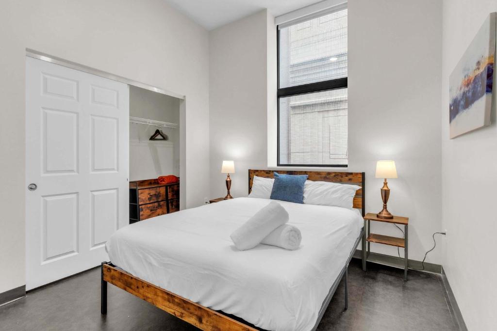 Un dormitorio con una cama con sábanas blancas y una ventana. en CozySuites Modern 1BR in Downtown Pitts #20, en Pittsburgh