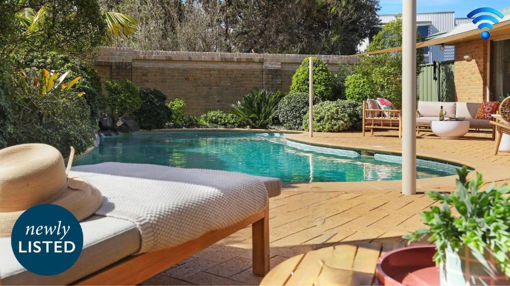 Una piscina en un patio trasero con una cama delante de ella. en Coolburra, en Culburra Beach