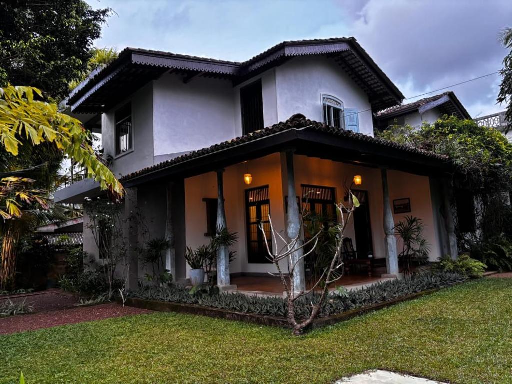 a white house with a lawn in front of it at Inura Villa in Ambalangoda