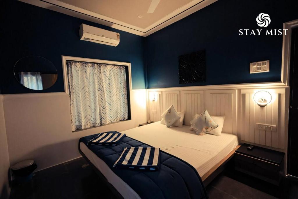 a bedroom with a bed with blue walls and a window at Pearl Castle Villa I Staymist in Nagaon