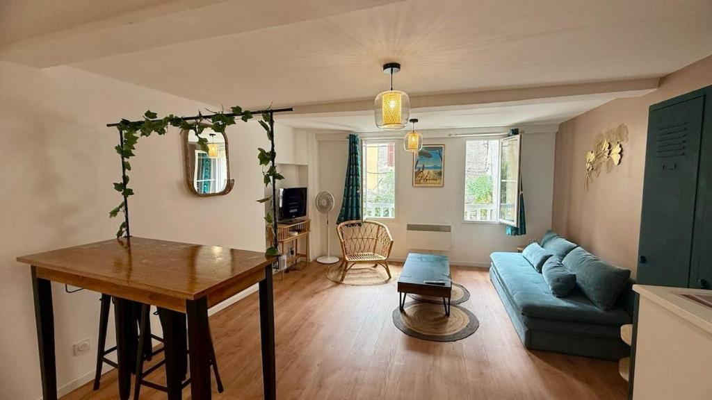 Una sala de estar con un sofá azul y una mesa. en Les Templiers - Downtown and private garage, en Hyères