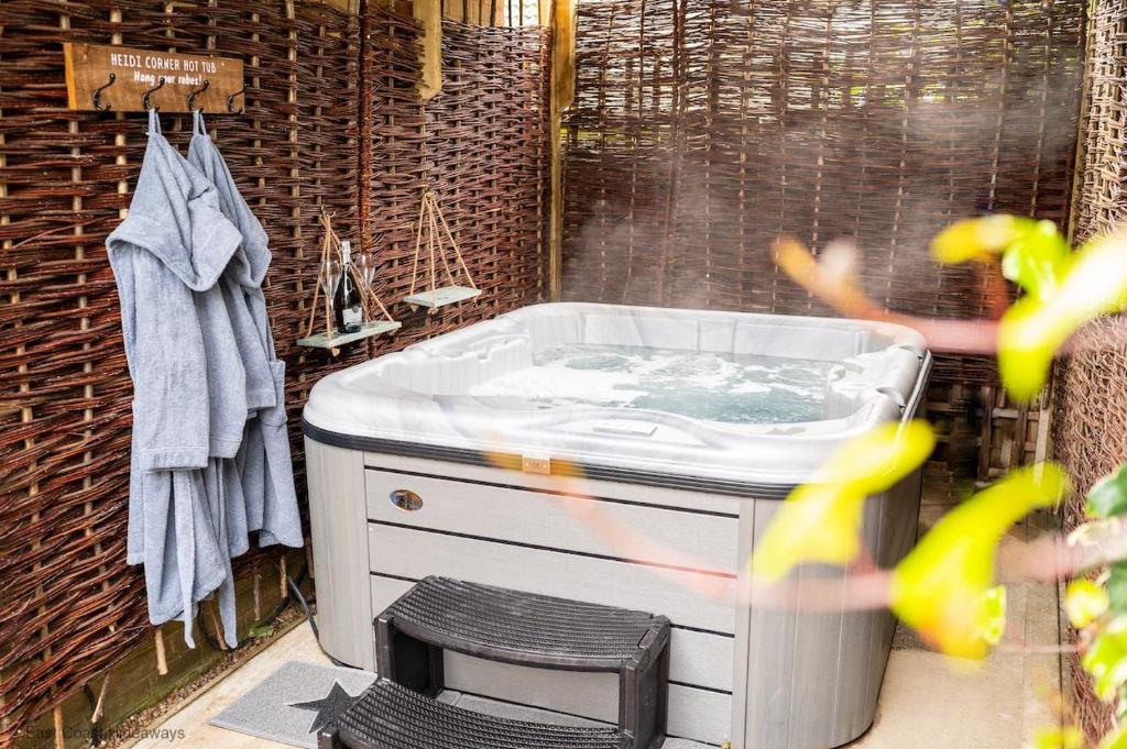 a bathroom with a bath tub with a stool at Dog friendly cottage with hot tub under 350 steps to dunes in Winterton-on-Sea