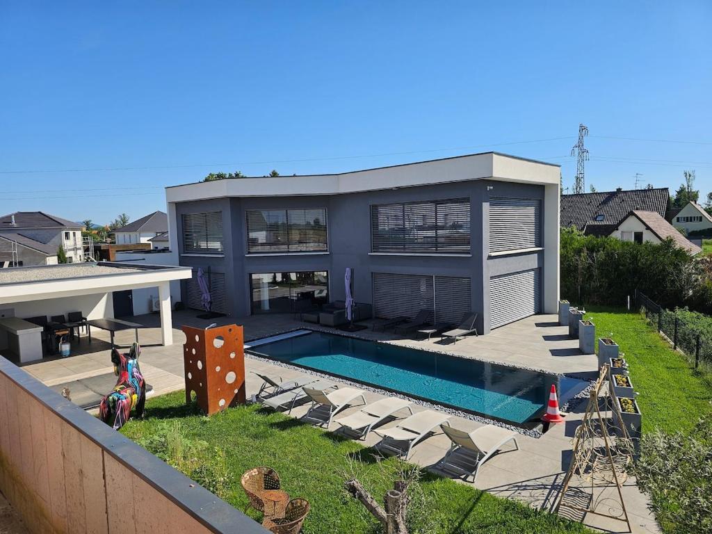 a large house with a swimming pool and chairs at Villa "Colmar" Spa and Free vine test in Raedersheim