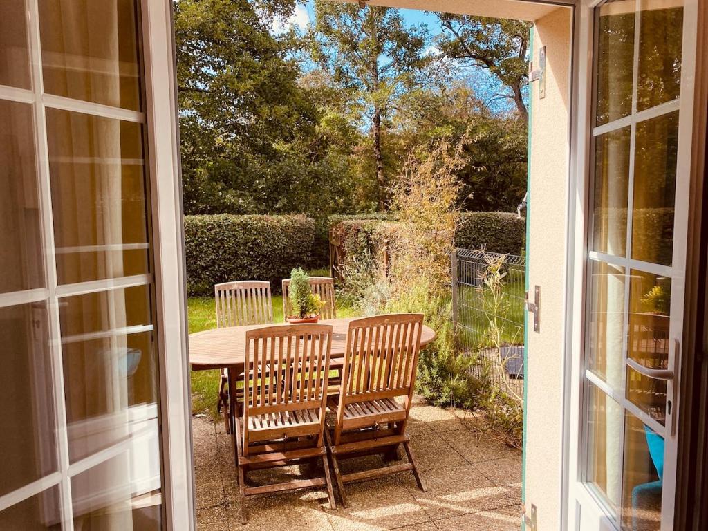 an open door to a patio with a table and chairs at Serena Entre mer et forêt in Camiers