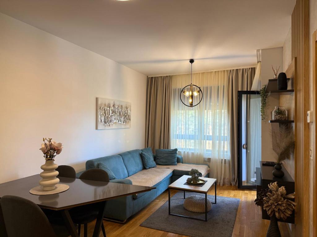 a living room with a blue couch and a table at Leo Pine Lux Apartments in Zlatibor