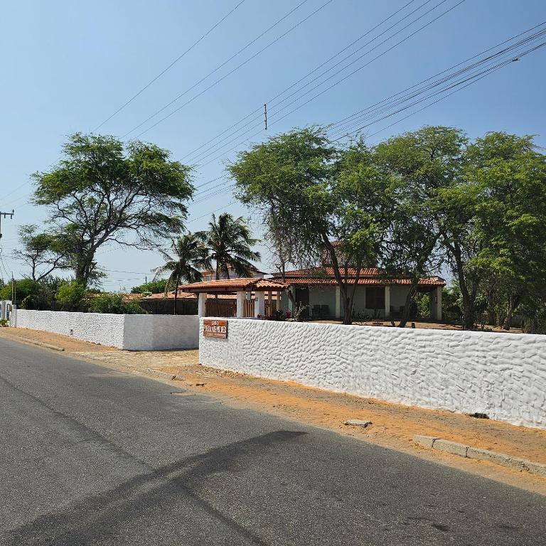 a white wall next to a road with a house at Pousada Mae Natureza Icapuí in Icapuí