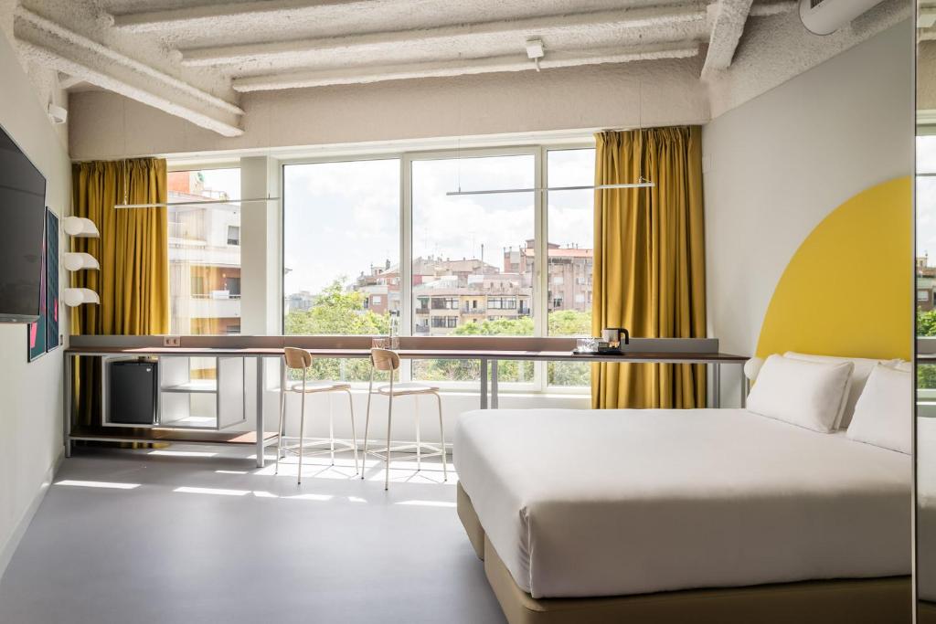 a hotel room with a bed and a large window at BYPILLOW Flamant in Barcelona