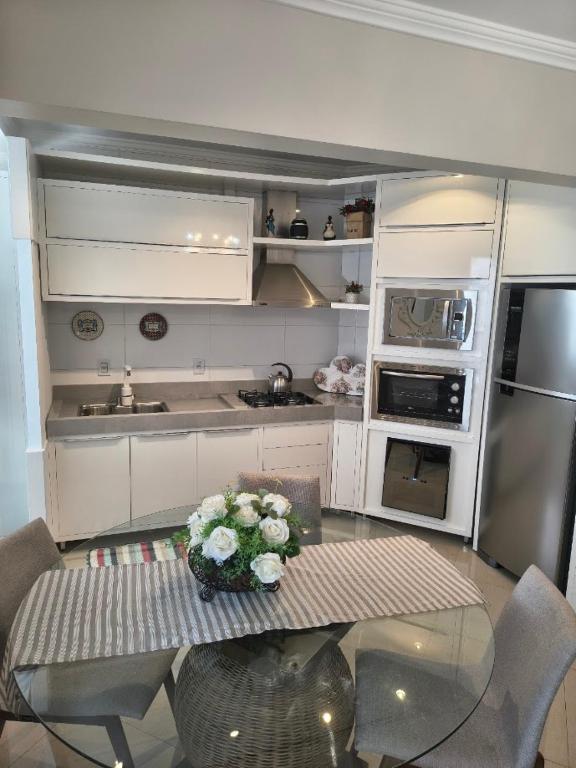 a kitchen with a table with flowers on it at Apartamento aconchegante com ar, secadora e adega in Piratuba