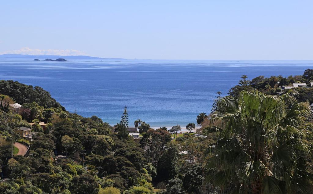 a view of the ocean from a hill with trees at Palm Waiheke Island Resort in Palm Beach