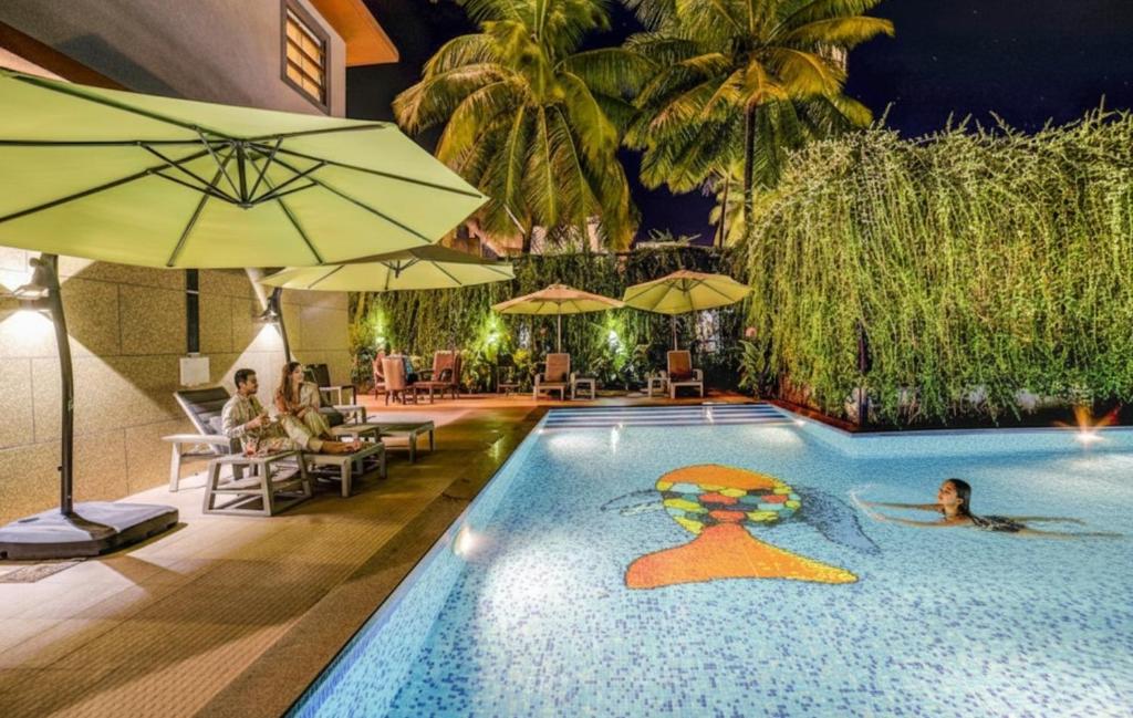 una piscina en un hotel con una persona en el agua en Oriva Sarala Crown - 500M From Calangute Beach, en Calangute