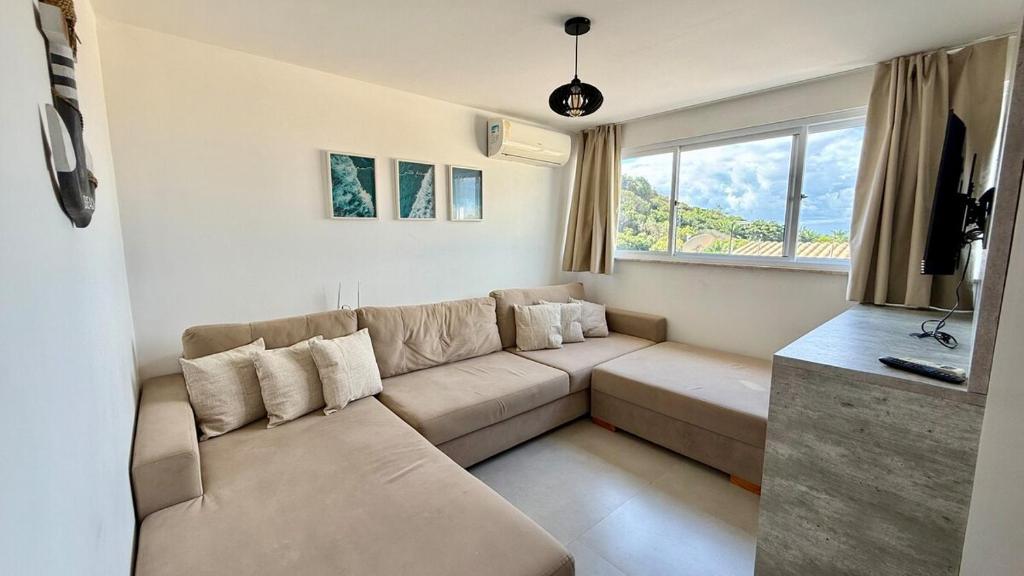 a living room with a couch and a large window at Casa Oxente - 2da praia condominio com piscina in Cayru