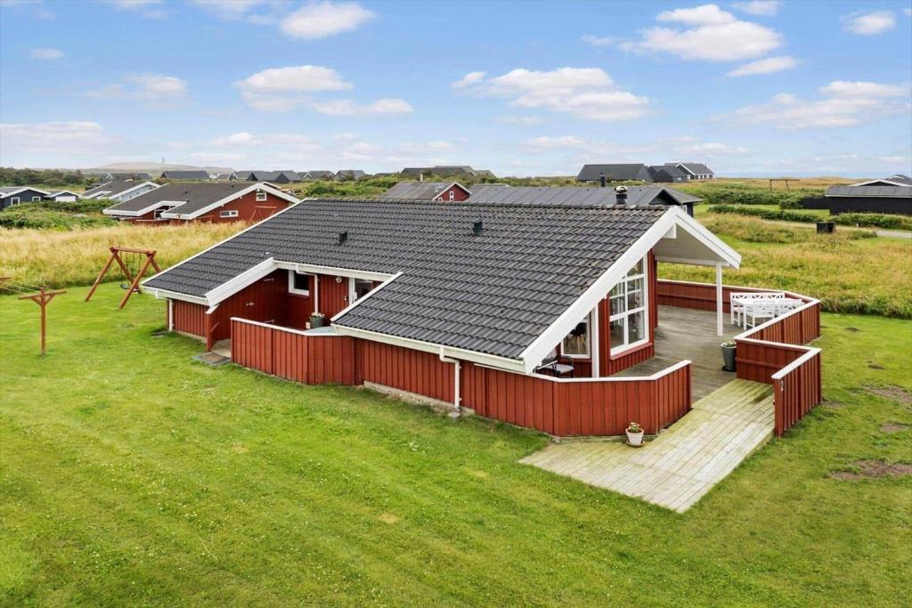 a red house with a roof on a green field at LN2020-Hjorring-Fjorden-2 in Lønstrup