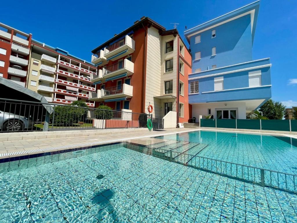 a swimming pool in front of a apartment building at Comfortable flat with shared pool in Porto Santa Margherita di Caorle