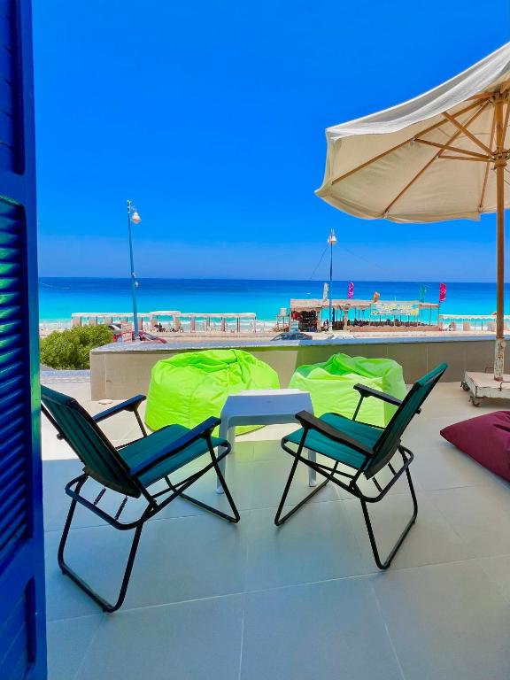 two chairs and an umbrella on a balcony with the beach at Blue House villa in Marsa Matruh