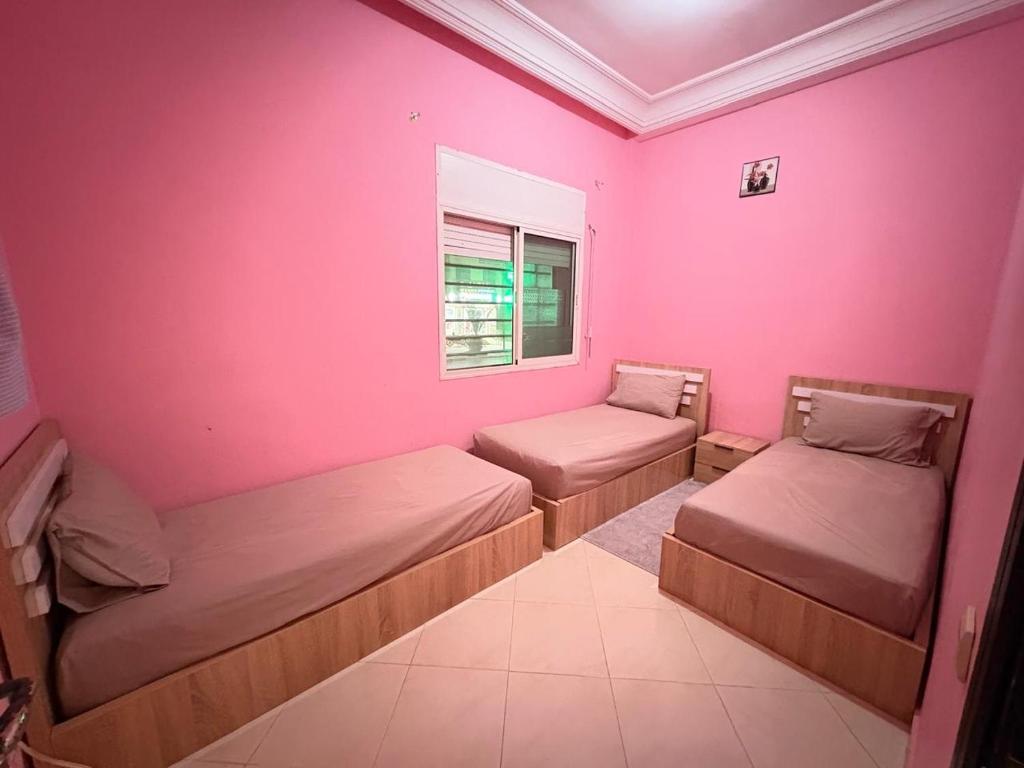 - 2 lits dans une chambre avec un mur rose dans l'établissement réside, à Oulad Akkou