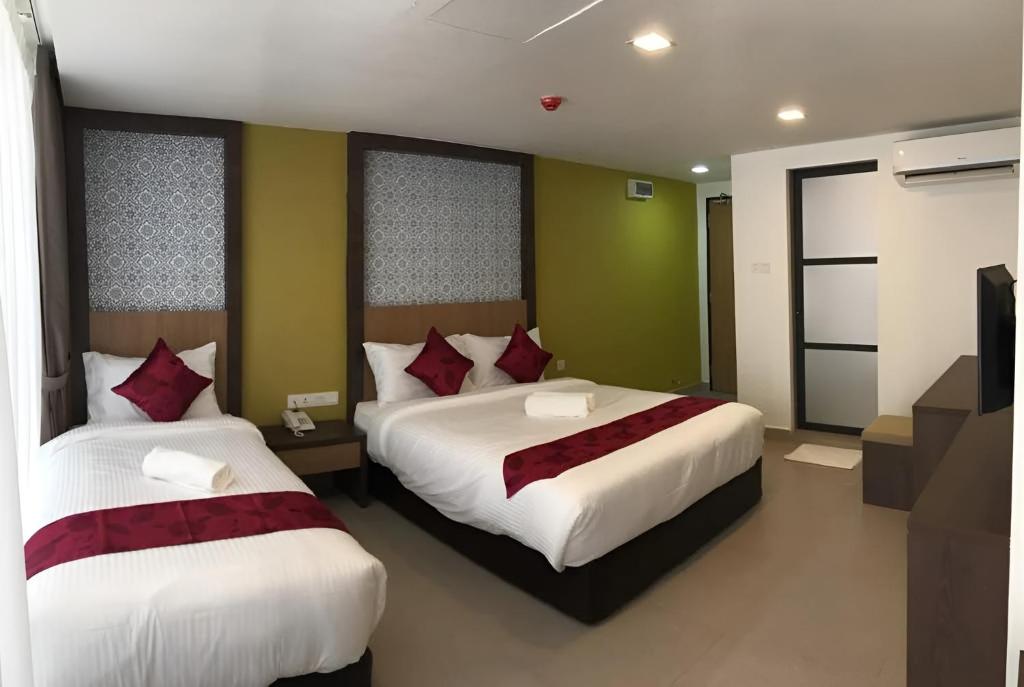 a bedroom with two beds with red pillows at Elite Hotel KL Sentral in Kuala Lumpur