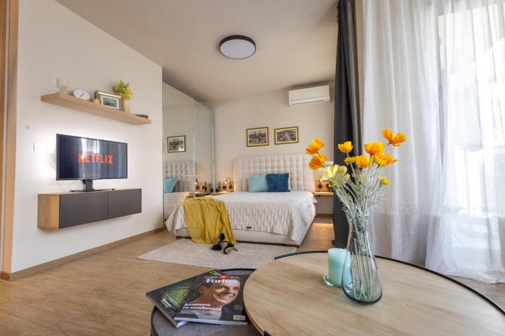 salon z łóżkiem i stołem z kwiatami w obiekcie Azur Alegria Studio by RV Apartments - free parking & pool w miejscowości Sweti Konstantin i Sweta Elena