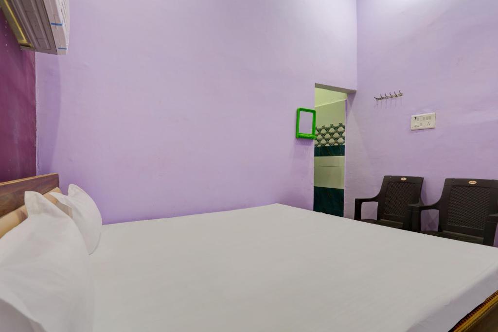a white bed in a room with two chairs at Hotel O Chaudhary Hotel in Tatārpur
