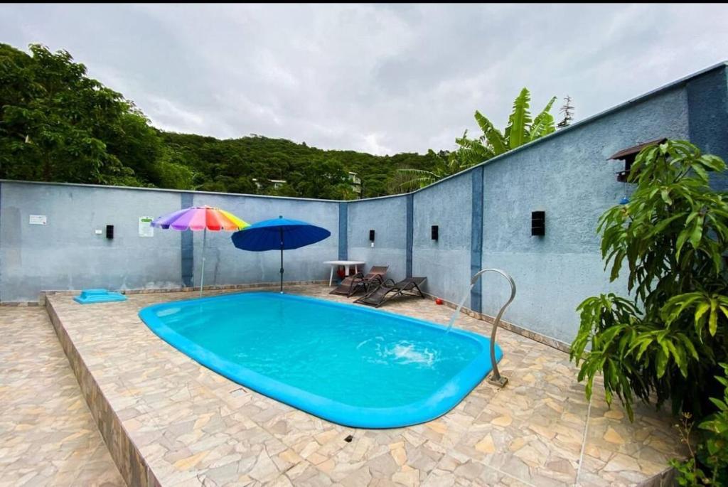 una piscina blu con un ombrellone, un tavolo e due ombrelloni di cód 164 - Casa de Praia com Piscina a Governador Celso Ramos