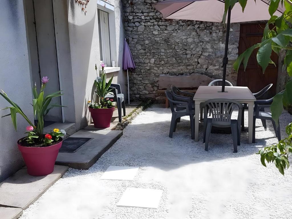 a patio with a table and chairs and an umbrella at La Maison Defanny - 1 in Muides-sur-Loire