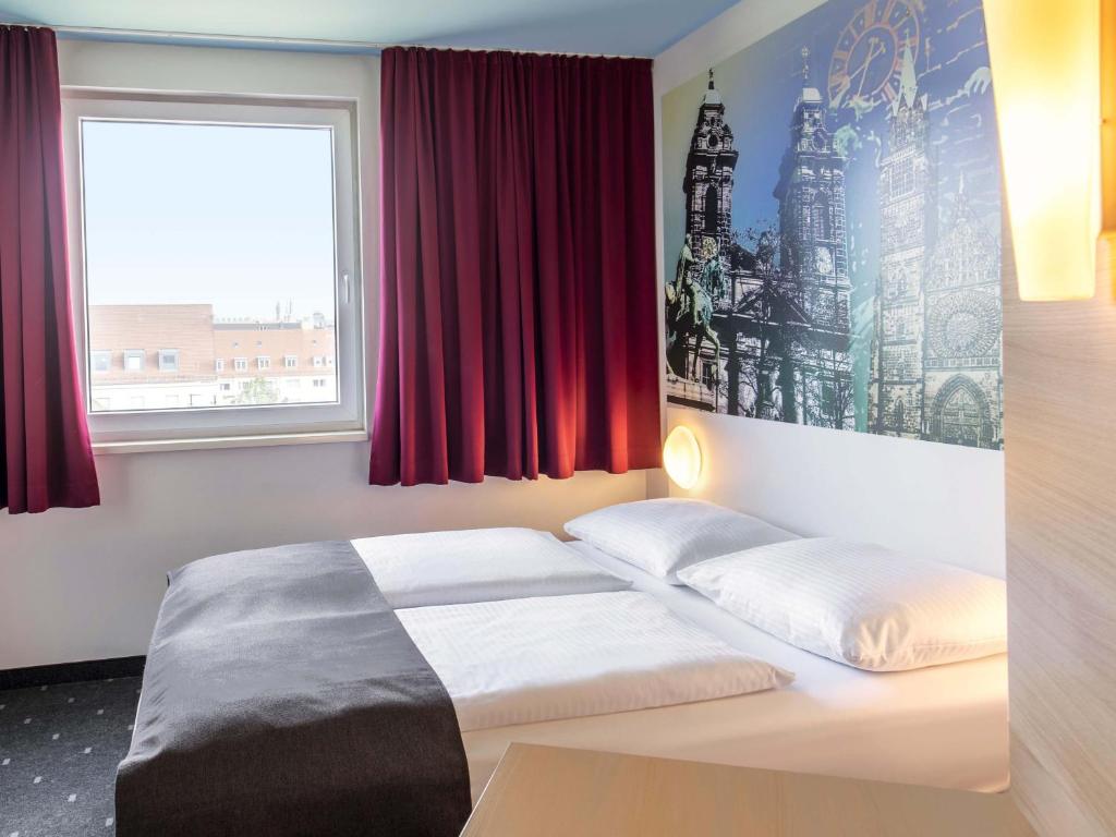 una cama en una habitación con una ventana roja en B&amp;B Hotel Nürnberg-City, en Núremberg