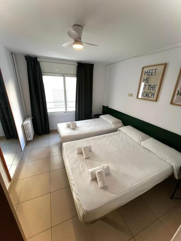 a bedroom with two beds and a window at Hostal Blanc Lloret in Lloret de Mar