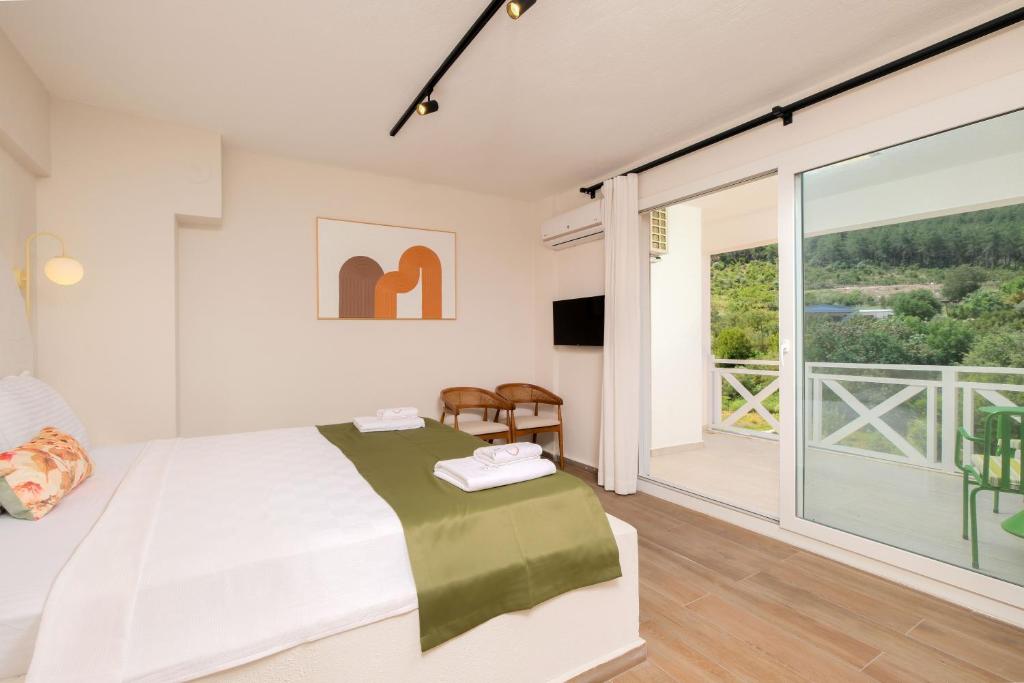 a bedroom with a bed and a large window at Tütsü Pension & Suites in Eskiömerler