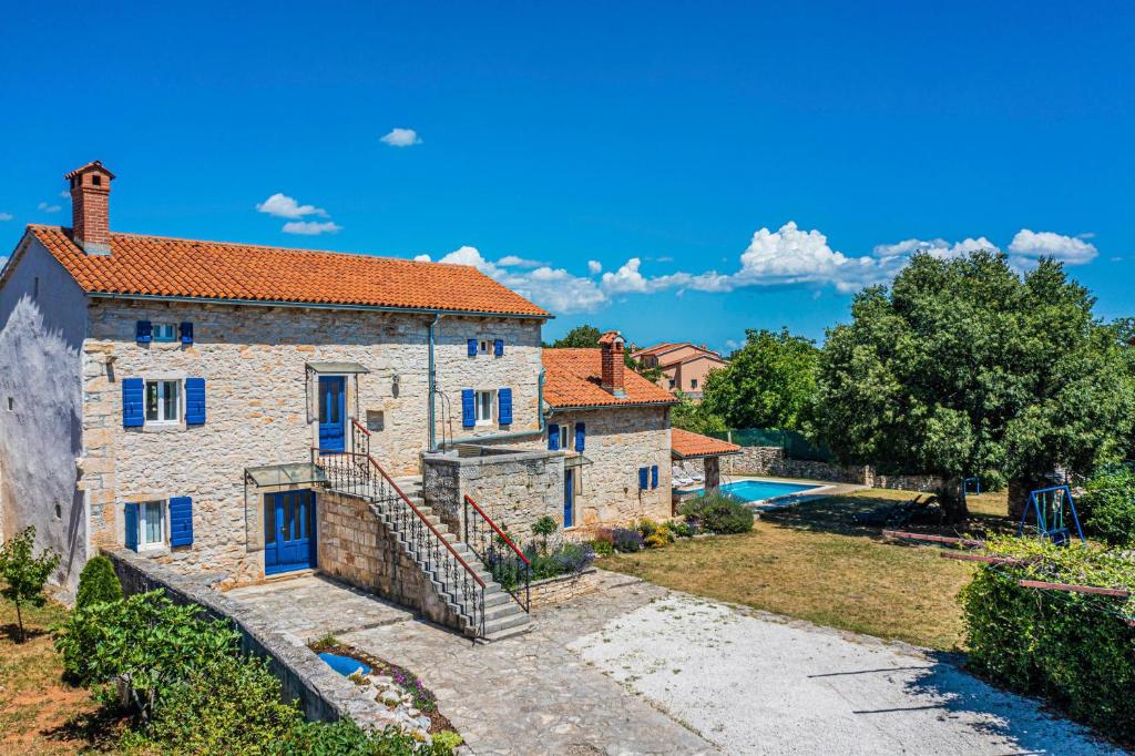 une maison en pierre avec des portes bleues et une cour dans l'établissement Kutić in Štokovci (Haus für 10-15 Personen), à Svetvinčenat