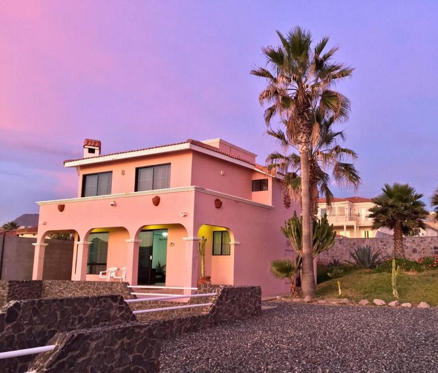 a pink house with a palm tree in front of it at Oceanfront - Casita Rosa in Puerto Nuevo