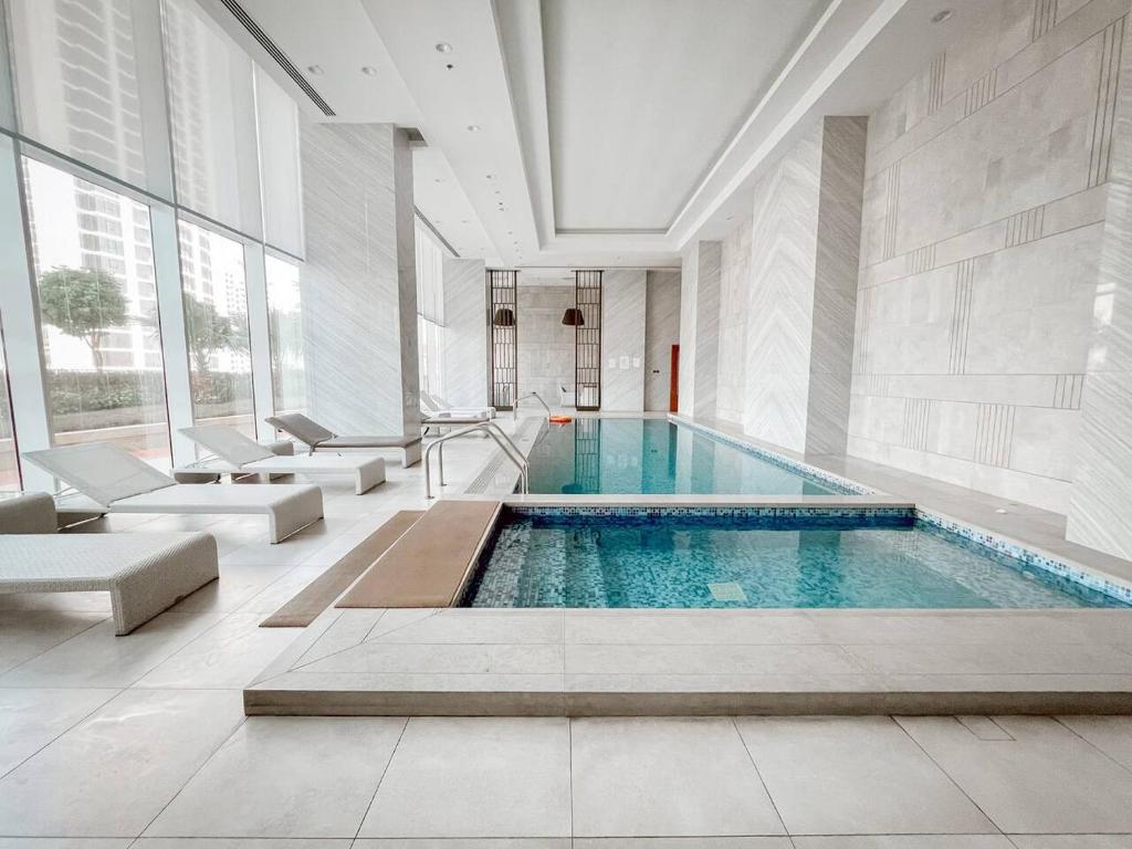 a swimming pool in a building with chairs and a couch at Hive Stayz - 1 Bedroom in Catamaran Tower in Sanābis