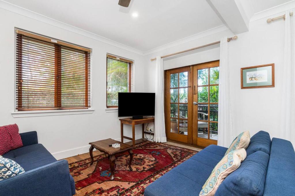 een woonkamer met een blauwe bank en een tv bij Sandy Bottoms in Brunswick Heads