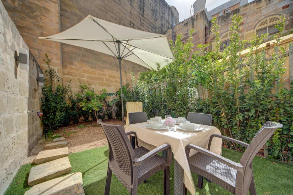 a table and chairs with an umbrella in a garden at Casa Elena, Private Garden, Office,1 Minute to the Sea by Haven & Keys Malta in Sliema