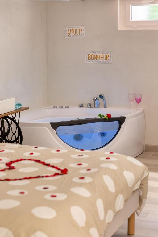 a bathroom with a tub and a table with flowers on it at L'Escapade Enchantée - Spa, Cheminée et Cinéma in Tournedos-Bois-Hubert