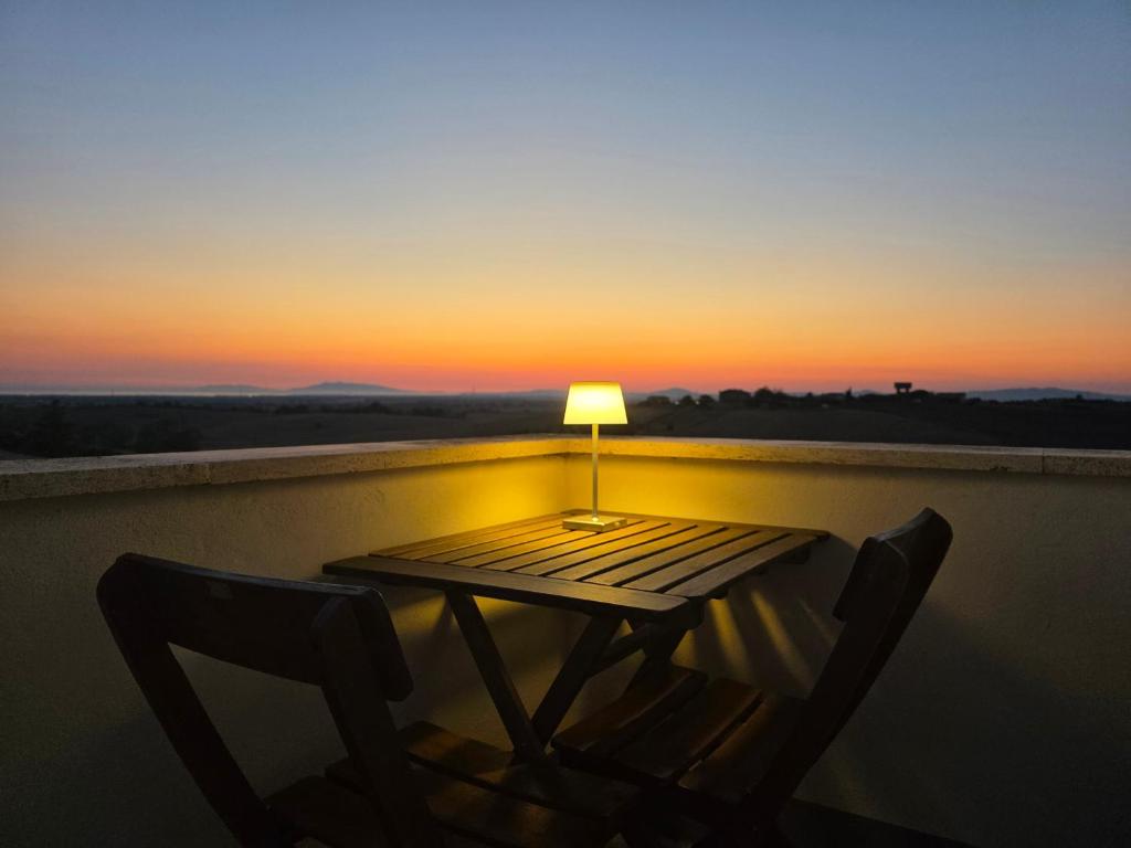 a table with two chairs and a lamp on a balcony at Il casale di Sere Tarquinia in Tarquinia