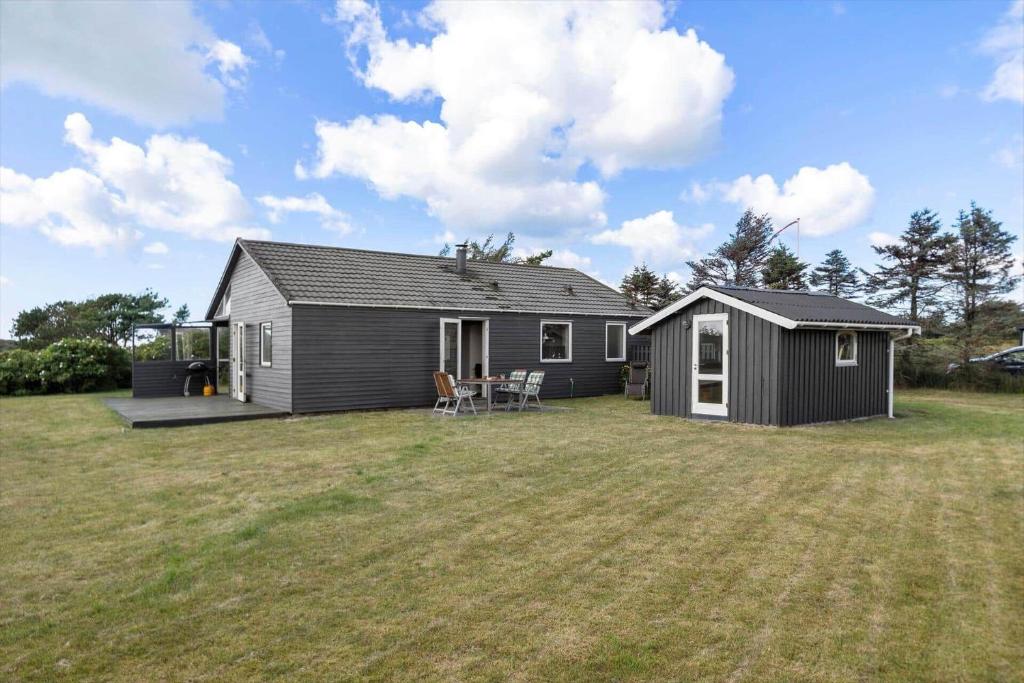 een klein zwart huis met een tuin en een huis bij LN2032-Hjorring-Krattet-9 in Lønstrup