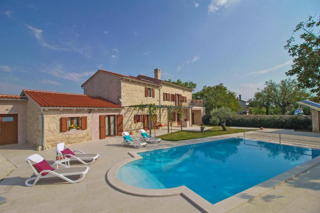 une piscine avec deux chaises et une maison dans l'établissement Villa Marija in Pekici (Haus für 8-10 Personen), à Svetvinčenat
