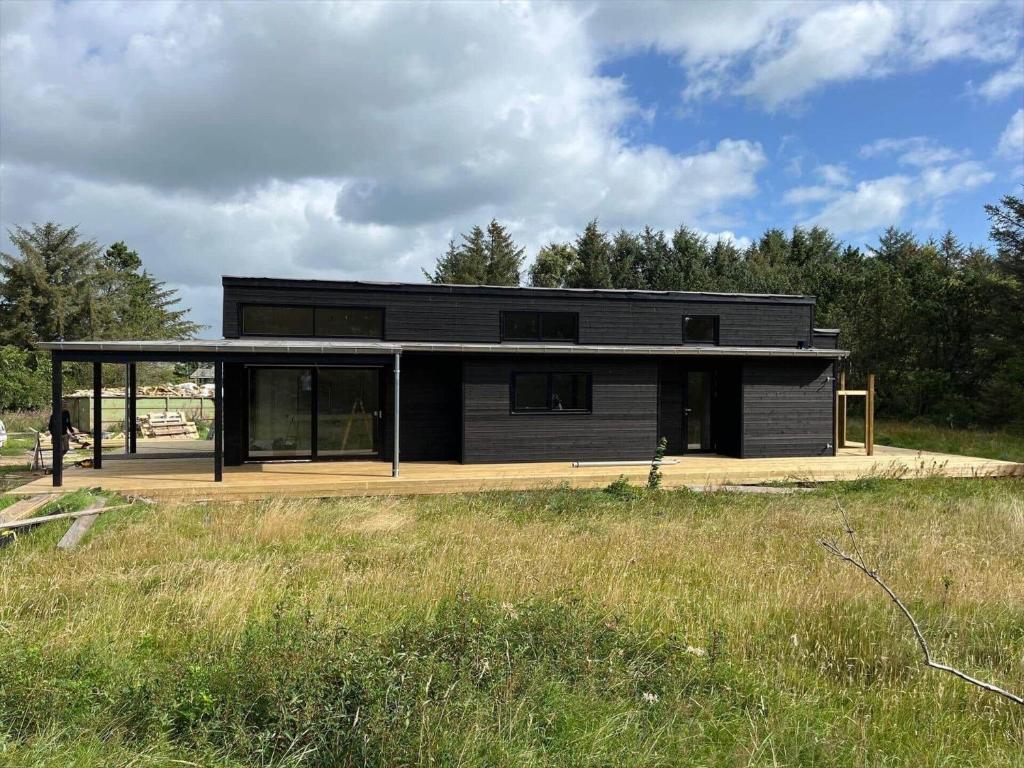 een groot zwart huis met glazen ramen in een veld bij JB365-Fjerritslev-Hedestien-9 in Torup Strand