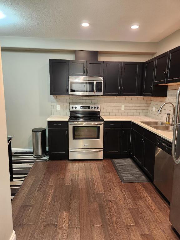 a kitchen with black cabinets and stainless steel appliances at Oasis at Heritage in Fort McMurray