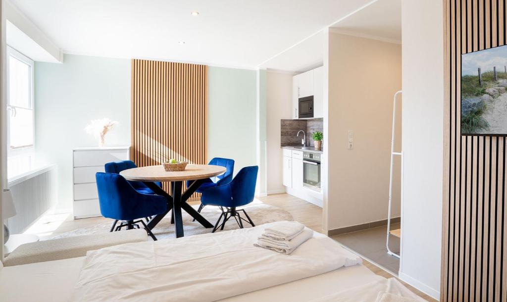 eine Küche und ein Esszimmer mit einem Tisch und blauen Stühlen in der Unterkunft Das Solaris Beach Apartment 20 mit Garten, Sauna und hundefreundlicher Ausstattung in Grömitz